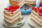 Plates with pieces of delicious strawberry cake on wooden table, closeup