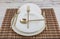 Plates and utensils, Plate, Bowl and golden cutlery on wicker american serving on dining table, side view. Modern craft ceramic