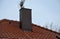 Plating the chimney on the roof of burnt tiles. chimney protection against rain, frost and snow with a brown plate. The tinsmith c