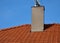 Plating the chimney on the roof of burnt tiles. chimney protection against rain, frost and snow with a brown plate. The tinsmith c