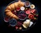 a platter of fruit cheese and croissants on a black background