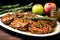 platter of pork chops topped with apple sauce next to rosemary sprigs