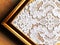 Plauener spitze (Plauen lace) handmade doily on wooden background in the golden frame