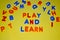 Play and learn words written with different colored letter blocks scattered on a yellow background