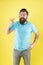 Play it loud. Bearded man point at headphones yellow background. Hipster listen to music in stereo headphones. Using