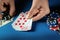 The player bets on a winning combination royal flush in poker game on a blue table with chips and money in a club