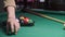 The player collects billiard balls with numbers on the billiard table. Sports game of billiards on a green cloth