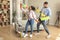 Playful african american spouses singing during housecleaning, using mop and duster as microphones, tidying home