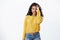 Playful alluring dark-skinned female model wear yellow sweater jeans, winking sassy and show tongue, hold circled