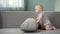 Playful baby girl having fun on sofa at home, active infant discovering world