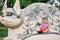 Playful baby holding red ball and sitting on stone cat statue in park