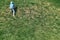 Playful boy goes up steep hill covered with lush grass