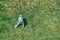 Playful boy goes up steep hill covered with lush grass