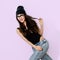 Playful brunette Girl in black body and beanie cap. Jeans. Tomboy style