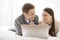 Playful business couple with laptop in hotel room