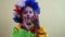 A playful and cheerful boy in a clown dress and a wig takes off his red false nose and throws it. Children`s animators for the hol