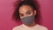 Playful, coquettish, tricksy look wearing reusable face mask African American charming girl in peachy t-shirt, to