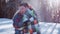 Playful couple having fun outdoors, young blonde girl throws up the snow, her boyfriend is hugging her under the fall of