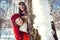 Playful couple in the snow hiding behind a tree trunk