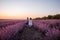Playful cute boy girl are playing in rows of lavender purple field at sunset. Small couple. Allergy