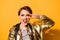 Playful excited fashion model with red lipstick, open mouth, gesturing and shoving v sign. She is in a golden jacket on