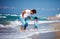 Playful father and toddler son having fun jumping in sea waves during summer vacation, family leisure activity games