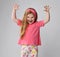 Playful, frolic redhead kid girl in pink t-shirt and colorful pants plays beast holding hands with claws up