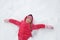 Playful girl playing in snow, making a snow angel