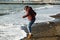 Playful girl touches sea wave boot on the beach
