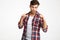 Playful handsome young man in checkered shirt showing thumb up g