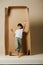 Playful indian boy stepping out of a cardboard box half twice as tall as him