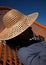 The playful interaction of light and shadow on a model's face, cast by a lattice wearing a wide-brimmed hat in