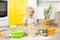 Playful kid boy with face in flour surrounded kitchenware and foodstuffs