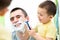 Playful kid and dad shaving together in bathroom