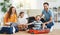 Playful kids in suitcases with parents on sofa behind