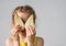 Playful little girl in sunny yellow dress hiding her eyes jokingly behing the halves of cutted pear. Close up studio