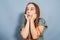 Playful little girl waiting for a gift. She is surprised, holding her hands under her chin. Gray background