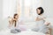 Playful mother and daugher have fun together, have pillow fight