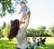 Playful Mother Lifting Baby Boy In Park