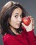 Playful multi-ethnic 20s girl holding an apple for pleasure in eating fruits