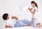 Playful pillow fight. A cheerful young ethnic couple having a pillow fight on their bed.
