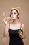 Playful pinup girl blowing party bubbles over yellow background