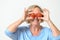 Playful senior lady holding tomatoes to her eyes