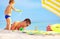 Playful son strews sand on father, beach