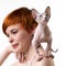 Playful Sphynx Cat looking up, stands on shoulder redhead young woman. Selective focus on foreground