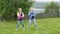 Playful teenager girls dancing on green meadow on forest and river landscape. Carefree girl teenagers having fun while