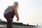 Playful Woman Crouching On Wooden Pole