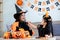 Playful young mother sitting on comfy couch in living room with cute little daughter tells spooky Halloween stories