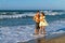 Playfull young couple in dress and shorts at the beach.