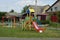 A playground with a colored slide stands in the green grass